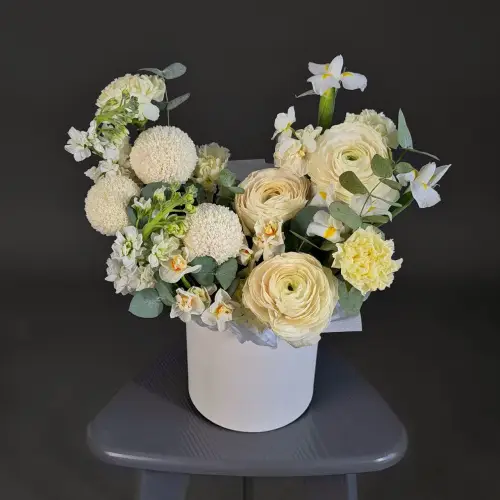 Цветочная композиция из ранункулюсов, ирисов и нарциссов в шляпной коробке