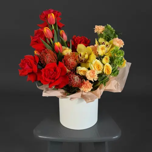 Цветочная композиция из тюльпанов, кустовой розы и нутана в шляпной коробке